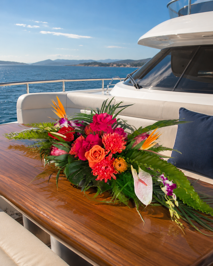 Composition florale basse sur la table de pont d'un yacht face à la mer